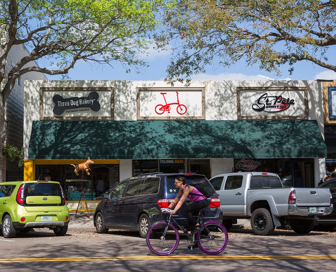 Woman riding bicycle in front of stores on St. Petersburg street.